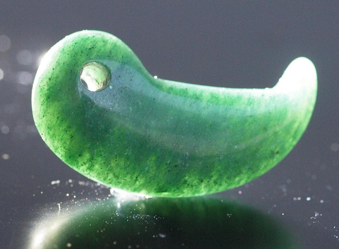 光にかざすと薄緑の細い帯状紋が出現、頭・胴の間には沈線、ずんぐり形の勾玉　沖縄の